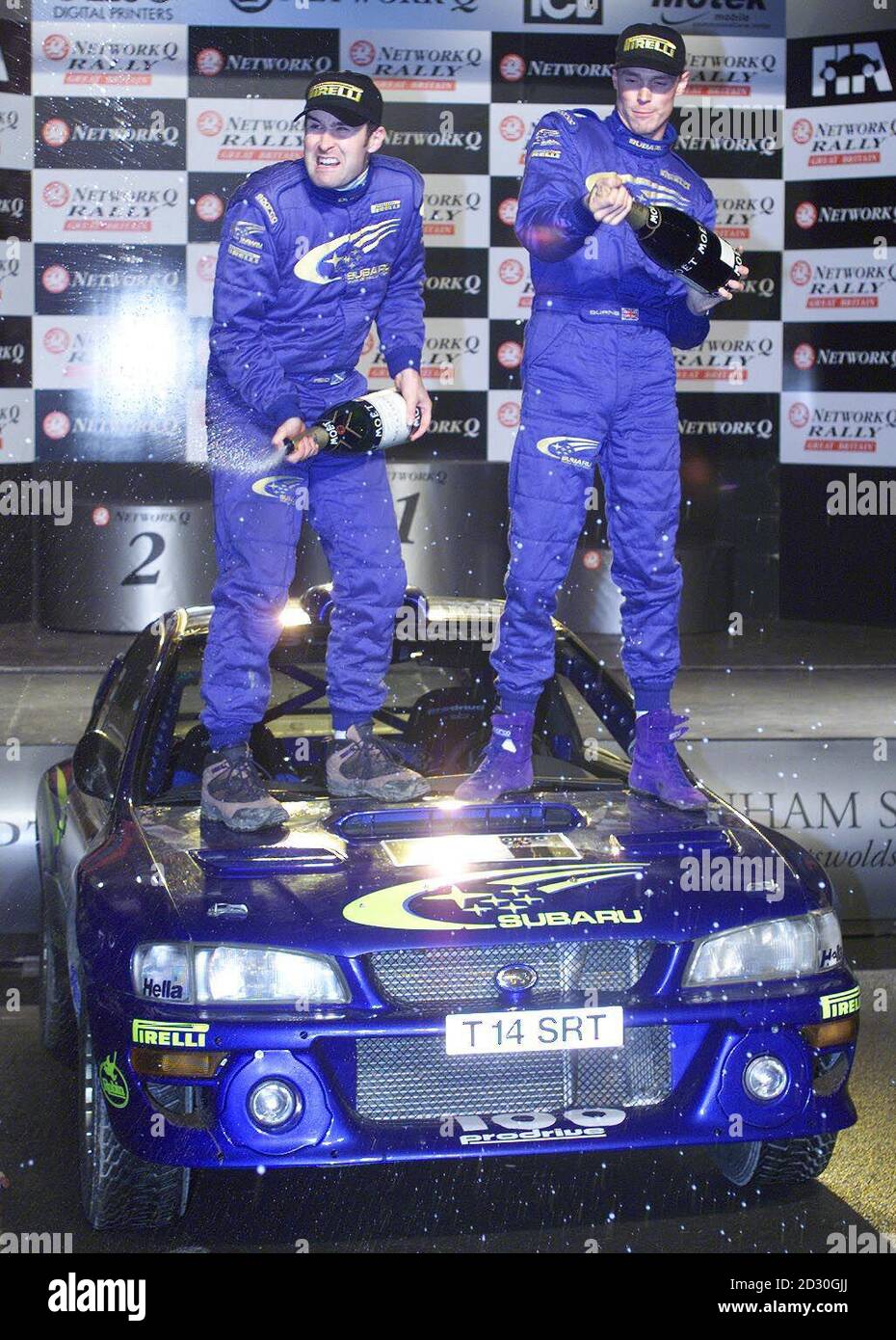Richard Burns (rechts) und Co-Pilot Robert Reid, die auf der Motorhaube ihres Subaru-Autos stehen, feiern mit Champagner, nachdem sie die Network Q Rallye Großbritanniens in Cheltenham gewonnen haben. Stockfoto