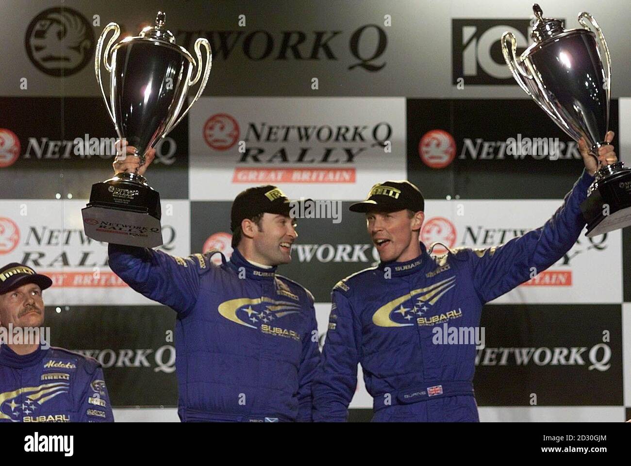 Richard Burns (rechts) und Co-Pilot Robert Reid (Mitte links) feiern den Sieg bei der Network Q Rallye Großbritanniens in Cheltenham. Der zweitplatzierte Fahrer, die Finnin Juha Kankkunen (ganz links), schaut auf. Stockfoto