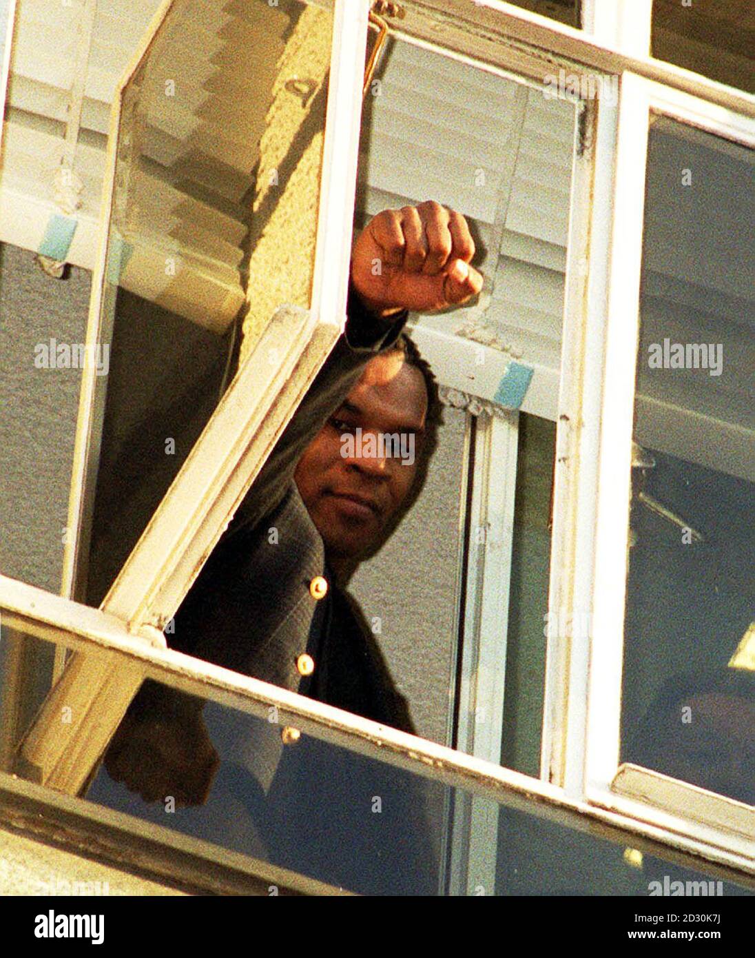 Boxer Mike Tyson grüßt die Menge vor der Brixton Polizeistation, wo er Zuflucht fand, nachdem er während eines Walks gedrängt wurde. Der umstrittene Kämpfer ist in London, um den britischen Boxer Julius Francis am 29. Januar 2000 zu bekämpfen. Stockfoto