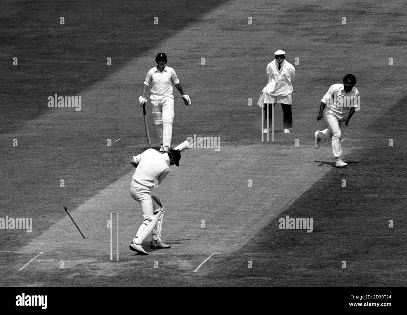 England Kapitän Tony Greig (unten) aus Stumpf wird geschickt fliegen, wie er eine Ente sammelt, während der schnellen Bowling von Andy Roberts (oben rechts) der West Indies, während ihres ersten Cricket-Test-Match in Trent Bridge, Nottingham. Stockfoto