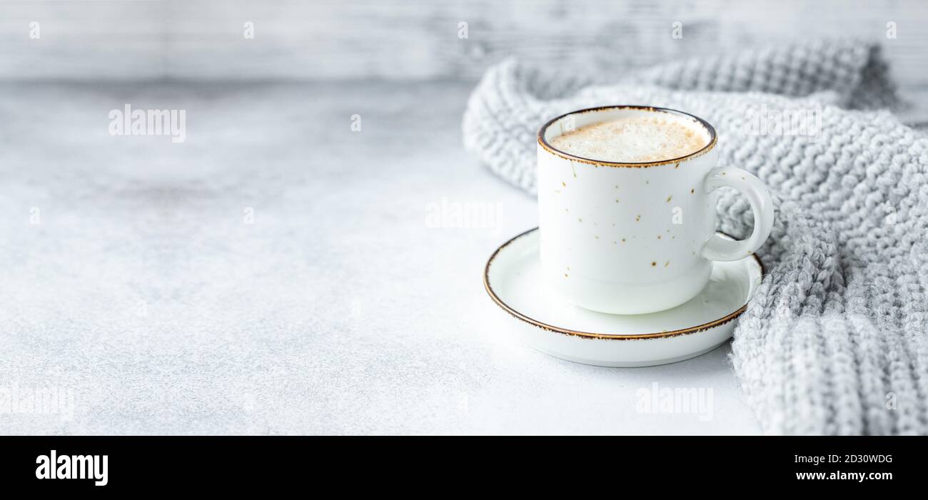Weiße Tasse mit Kaffee und Wollschal auf Stein Hintergrund. Winterkomposition im skandinavischen Stil. Platz für Text - Bild kopieren Stockfoto