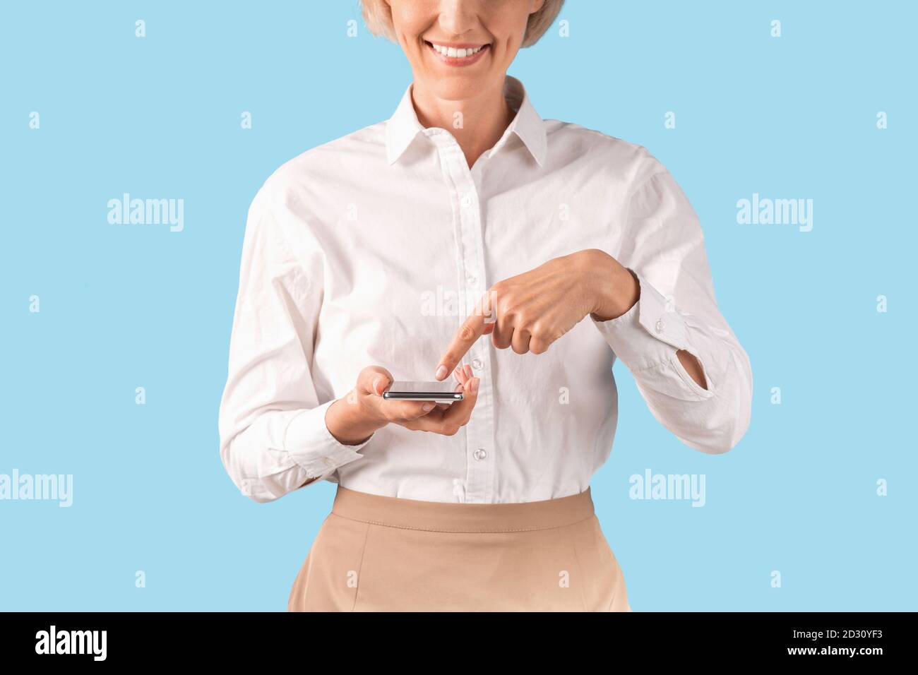 Nahaufnahme von Geschäftsfrau mit Handy, das online arbeitet oder Kommunikation mit dem Kunden auf blauem Studiohintergrund Stockfoto