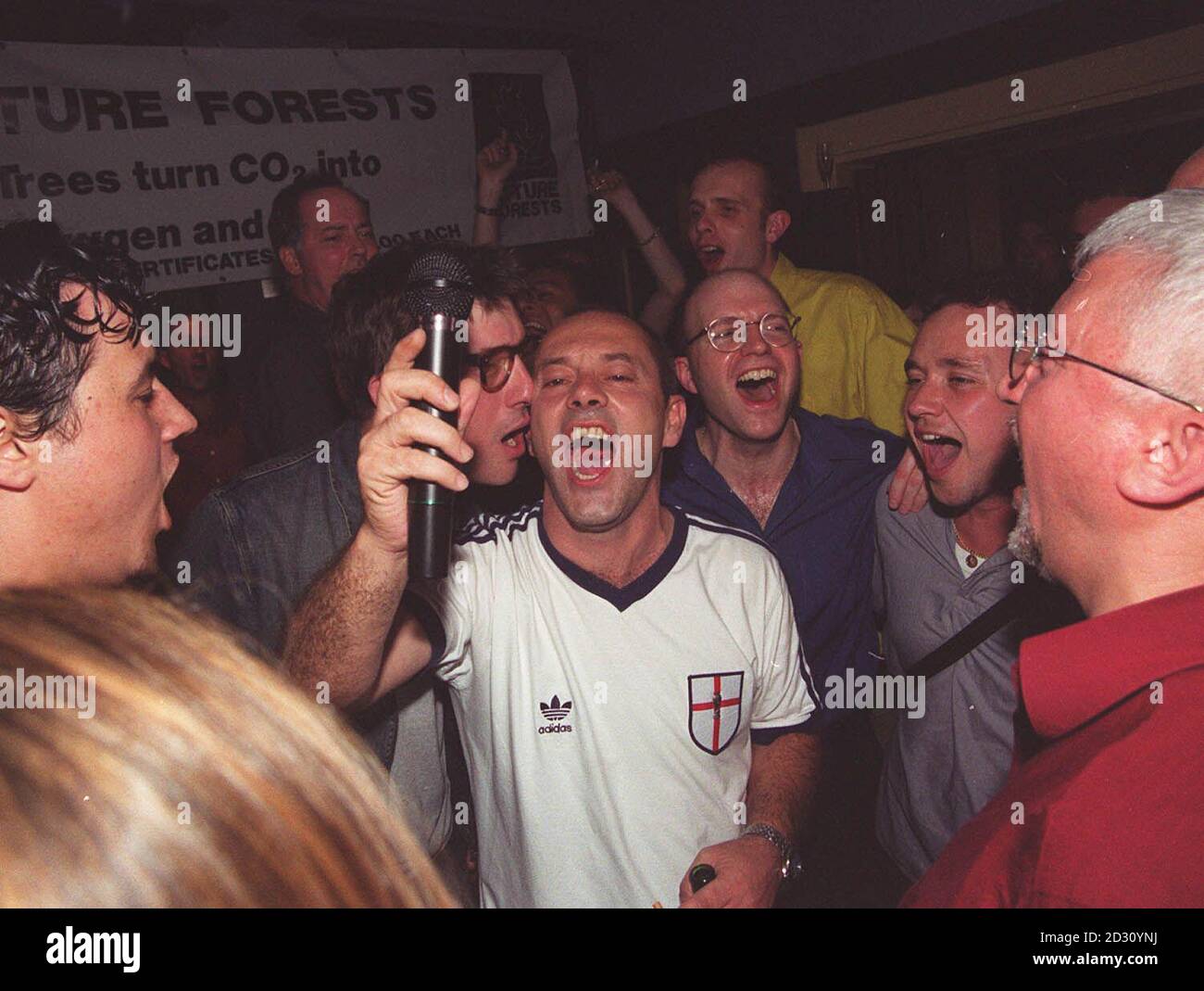 Schauspieler und Musiker Keith Allen, Mitte, von der Band Fat Les, feiert die England Euro 2000 Hymne, Jerusalem, von der Band nach ihrer inoffiziellen WM-Hymne, Vindaloo, bei einer Party im Groucho Club, London. * das Fat Les-Team wird mit zukünftigen Wäldern zusammenarbeiten, um Wälder im ganzen Land zu Pflanzen, um Kohlendioxid aus der Herstellung der Jerusalem CD zu absorbieren und es in Sauerstoff zu verwandeln, sagte die Band. Stockfoto