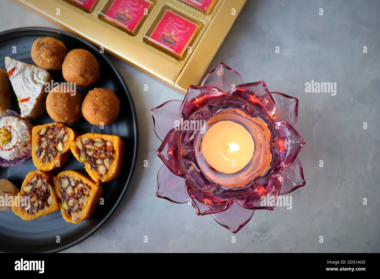 Verschiedene indische Süßigkeiten oder Mithai, Rava laddoo, Besan laddu, Trockenfrüchte Süßigkeiten in einem schwarzen Teller zusammen mit Happy Diwali Schokolade für Diwali Festival. Stockfoto