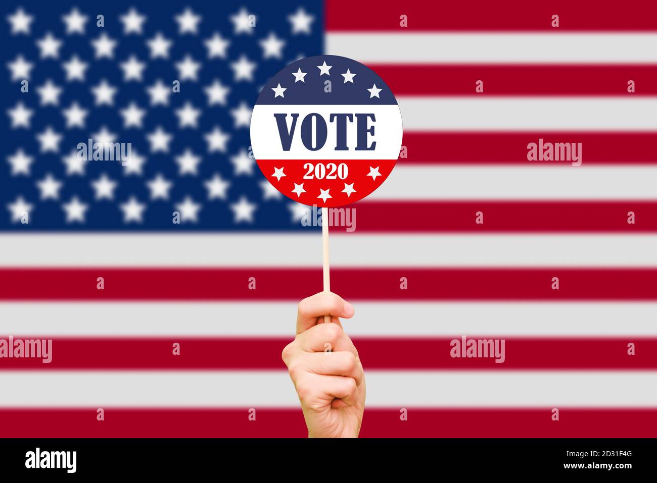 Hand und Knopf für die Wahl auf dem Hintergrund der amerikanischen Flagge. Die US-Präsidentschaftswahlen 2020. Wahltag in den Vereinigten Staaten von Stockfoto
