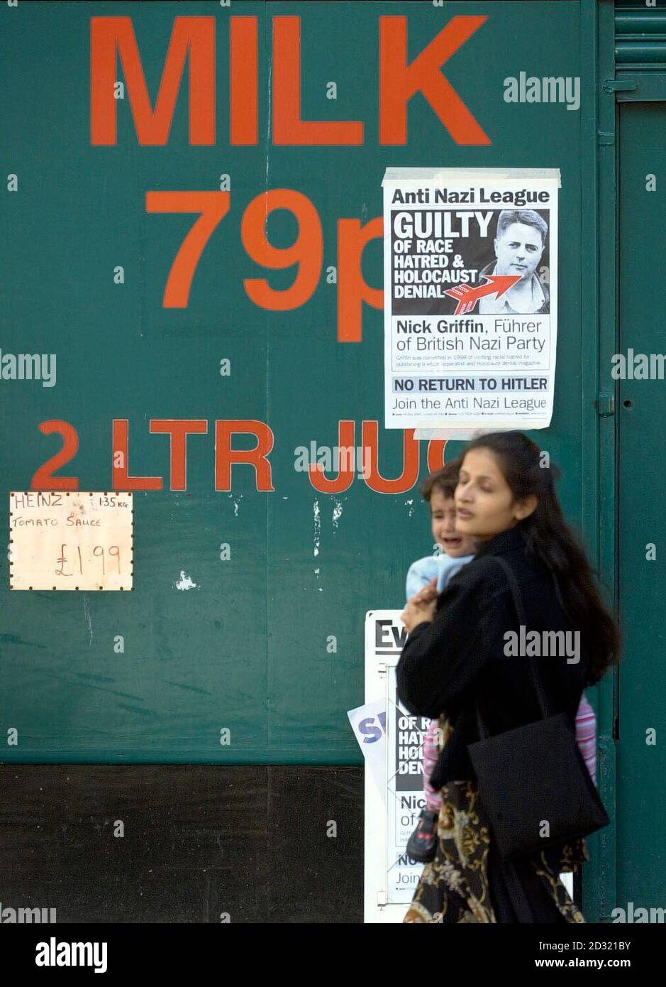 Eine Asiatin und ihr Kind gehen an einem antibritischen Plakat der National Party in der Gegend von Pollokshields in Glasgow vorbei, nachdem antirassistische Aktivisten begonnen hatten, die Gegend zu blättern, nachdem Gerüchten zufolge BNP-Anführer Nick Griffin in die Stadt kommen könnte. Stockfoto