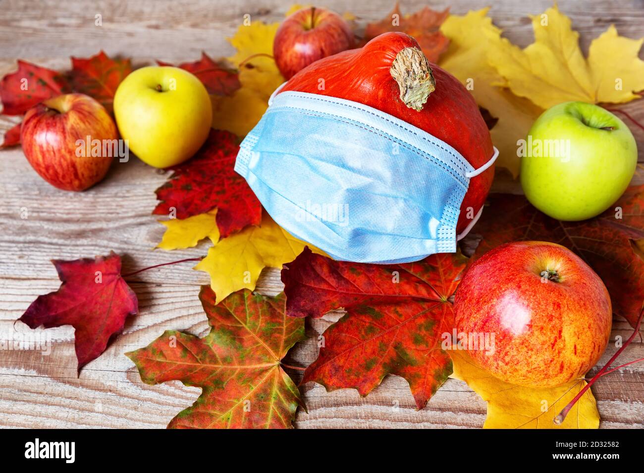 Eine Maske auf Herbstkürbis mit bunten Blättern, Gesundheits- und Hygienekonzept. Halloween Herbst Konzept mit Corona Virus Prävention. Stockfoto