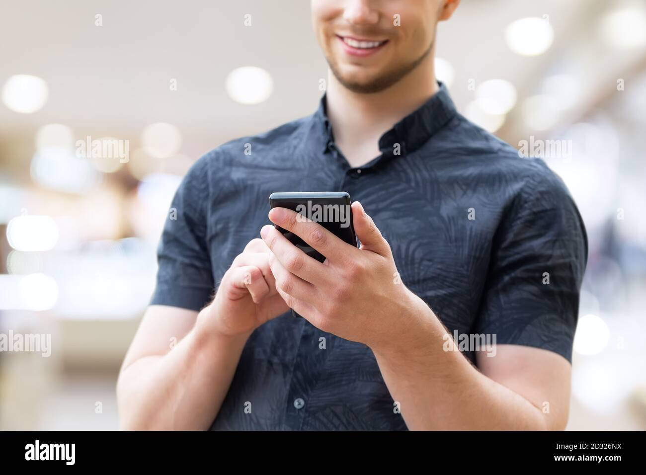Mann mit Handy, Nahaufnahme. Bild eines jungen Mannes mit einem Handy und lächelnd. Stockfoto