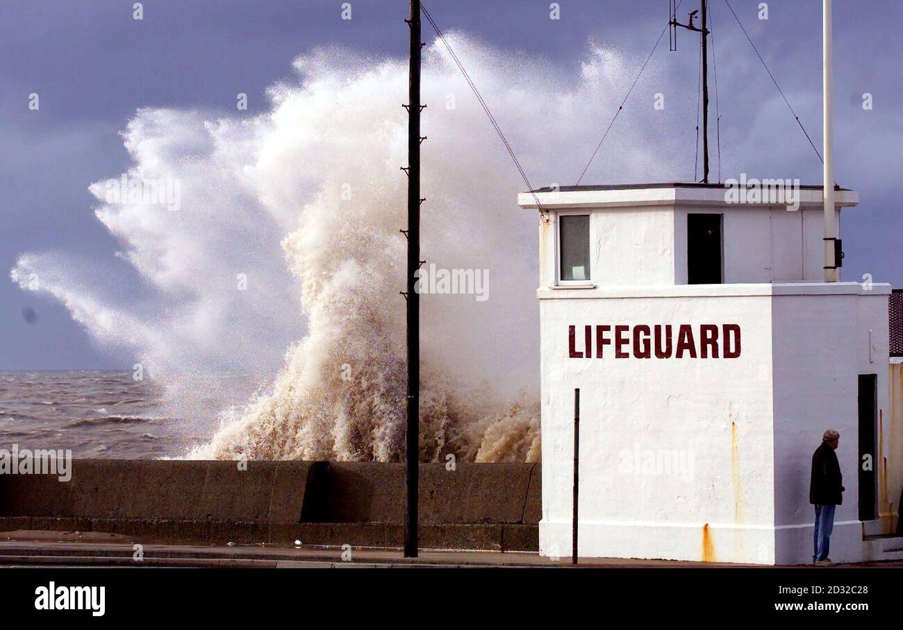 Ein Mann versteckt sich hinter einer Rettungsstation in New Brighton am Wirral, während riesige Wellen die Promenade an einem Tag schlagen, an dem das Land von Sturmwind und hohen Gezeiten getroffen wurde. * Schottland und der Westen nahm die Hauptlast der Sturmwinde mit Böen von 82 mph auf der Hebriden-Insel South Uist aufgezeichnet, und 72 mph in Mumbles in Südwales, sagte ein PA WeatherCenter Sprecher. Die Stürme sind weniger schwer als die heftigen Stürme am Montag, die acht Menschen getötet und Schäden verursacht Millionen von Pfund. Doch die Polizei warnte Autofahrer, auf den Straßen besonders vorsichtig zu sein und nur weiter zu fahren Stockfoto