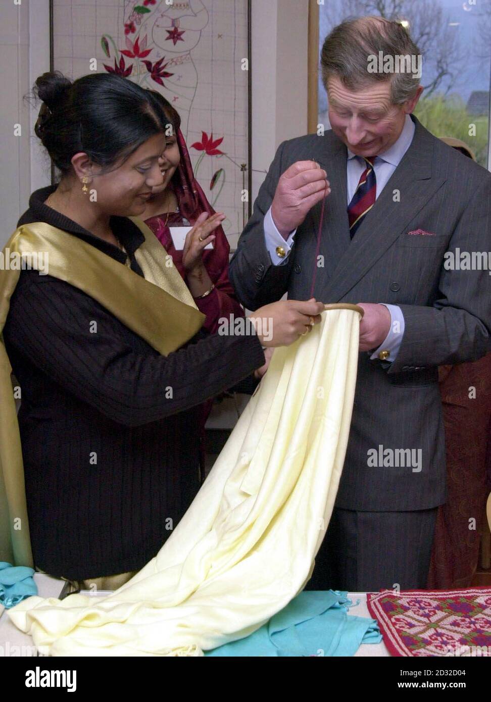Der Prinz von Wales hat sich beim Sticken eines Schals, der von Shafia Choudhury (links) angefertigt wurde, während eines Besuchs im Bromley by Bow Healthy Living Centre, East London, das er offiziell eröffnet hat, zu Eigen gemacht. Stockfoto