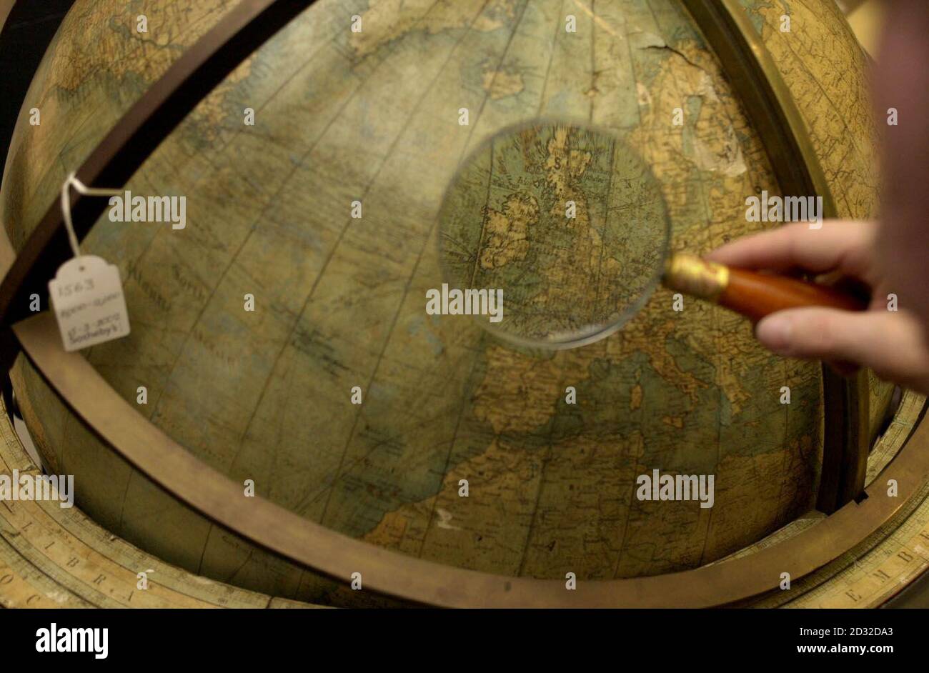 Ein Techniker von Sotheby studiert einen 30-Zoll-Erdglobus, der Mitte des 19. Jahrhunderts von W & A.K. Johnston hergestellt wurde und in der Verfilmung von J.K Rowlings "Harry Potter und der Stein der Weisen" durch eine Lupe bei Sotheby's im Zentrum Londons verwendet wurde. * ... Beide Artikel werden während Sothebys anstehender Versteigerung von Prop Art verkauft. Stockfoto