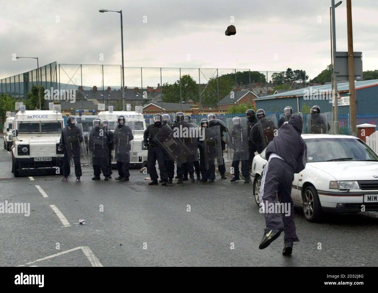 Ein katholischer Jugendlicher wirft einen Felsen auf die Polizei auf der Springfield Road, West Belfast. Die Polizei erlitt eine Flut von Benzinbomben, Feuerwerken und Ziegelsteinen, nachdem Beamte in einem nationalistischen Gebiet mit einem Plastikstab auf Demonstranten schossen, die eine Parade der Orangenen Ordnung Angriffen. * die Schwierigkeiten begannen, als katholische Demonstranten sahen, wie Orangemen einen umkämpften Teil der Springfield Road hinauf ging. Stockfoto