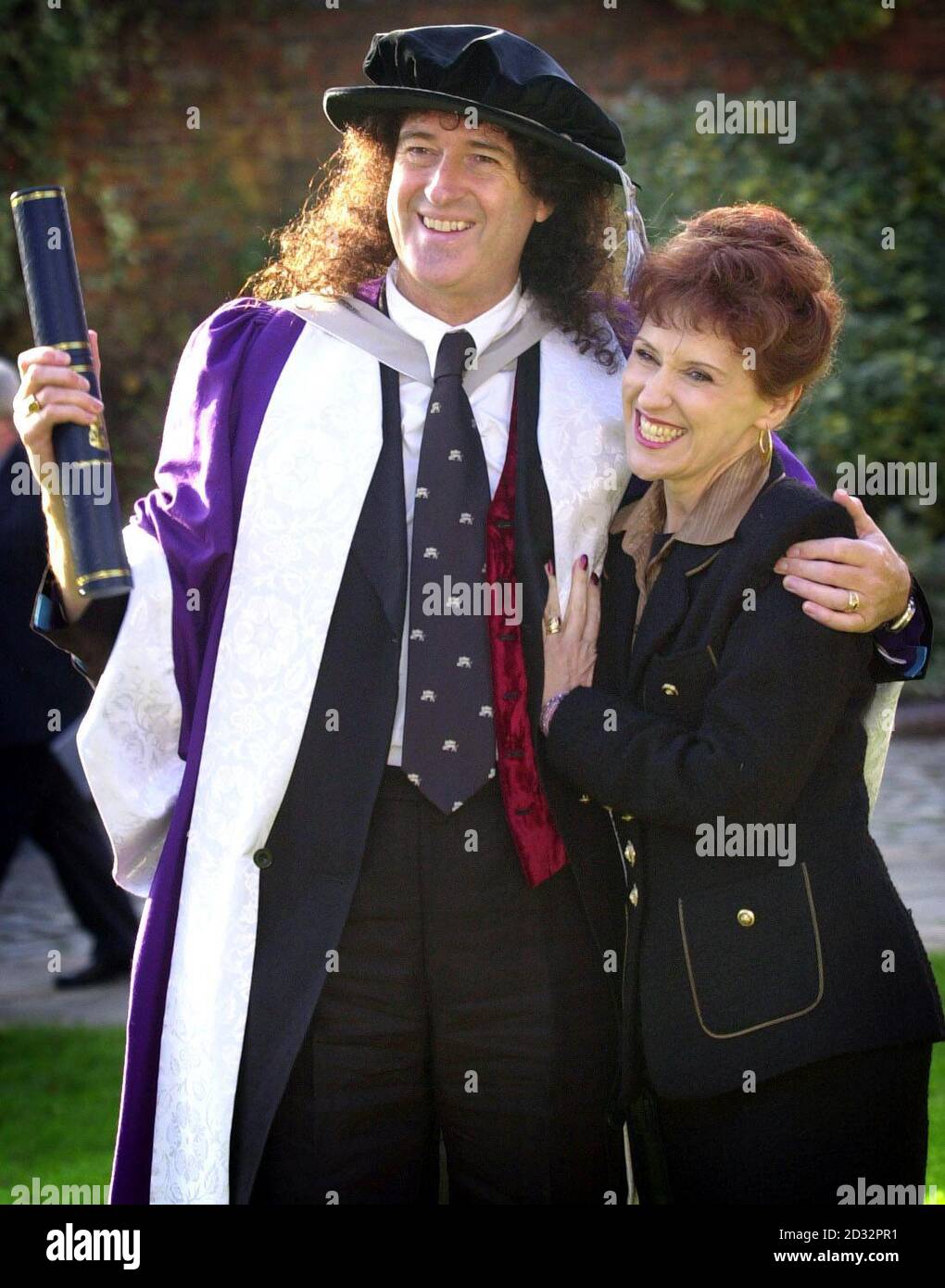 Queen-Gitarrist und Amateurastronom Brian May mit seiner Frau Anita Dobson vor der Kathedrale von St. Albans, nachdem er von der University of Hertfordshire die Ehrendoktorwürde für Wissenschaft erhalten hatte. * berühmter jetzt für Gitarren anstatt Sterne, Mai 55, war ein versierter Astronomie-Student am Imperial College in London. Er arbeitete an seiner Promotion, als seine Rockstar Karriere startete und während er ein großes Interesse an Astronomie er nie beendet den Abschluss. Stockfoto