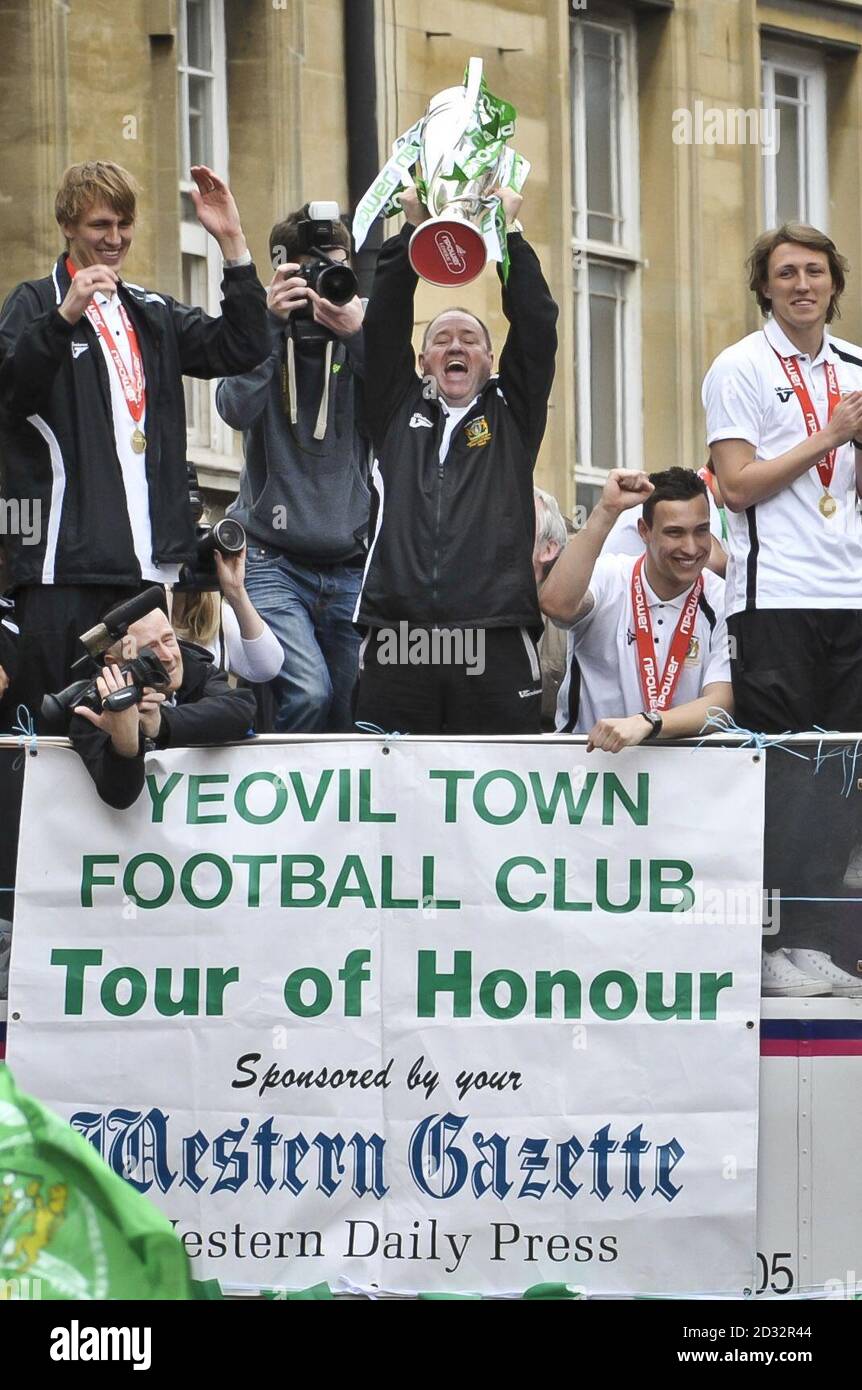 Der Yeovil Town Manager Gary Johnson hebt die Trophäe an Bord eines offenen Busses während der Yeovil Town's Tour of Honor durch die Silver Street in der Stadt Somerset. Stockfoto