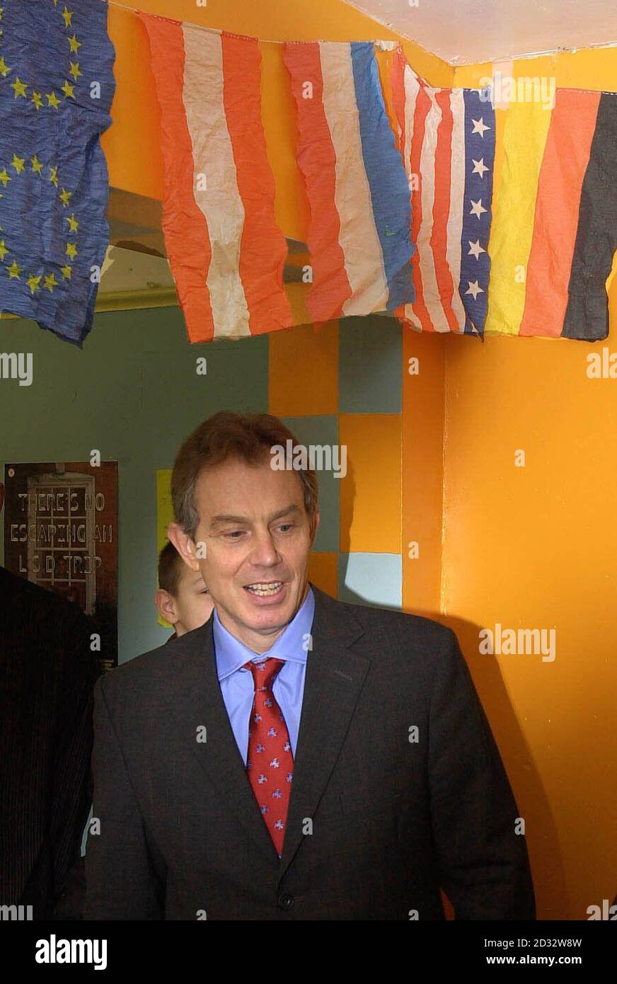 Premierminister Tony Blair steht bei einem Besuch in einem Jugendclub in Beeston, Leeds, unter einer Reihe internationaler Flaggen und EU-Flaggen. Stockfoto
