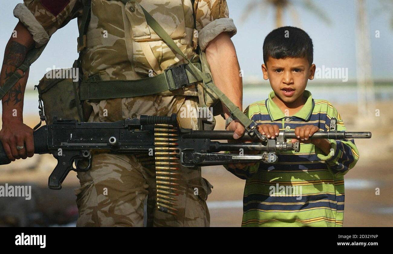 Ein kleiner Junge hängt an einem GPMG (General Purpose Machine Gun), das von einem Soldaten der C-Kompanie des 1. Bataillons des Parachute Regiments in Al Qurna, Irak, gehalten wird, während er und Kollegen von sieben Zugmaschinen zu Fuß in der Nähe des biblischen Gartens Eden patrouillieren. * heute ist es das erste Mal, dass die britische Armee zu Fuß patrouilliert hat und keine Helme trägt. Stockfoto