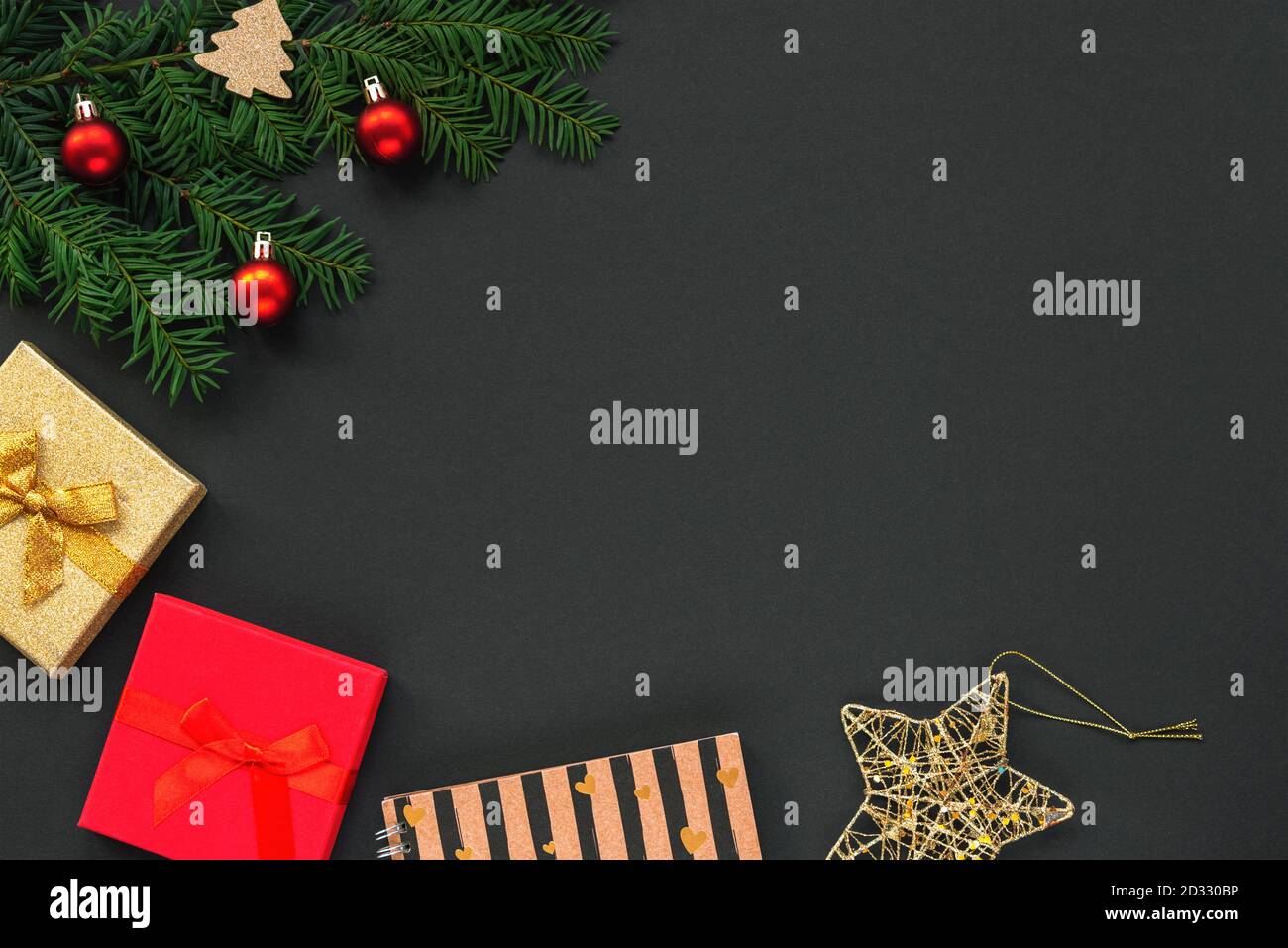 Festliche Weihnachtshintergrund mit Tannenbaum, Geschenke in Schachteln und Spielzeug auf schwarz. Draufsicht, flach liegend, Kopierbereich. Stockfoto
