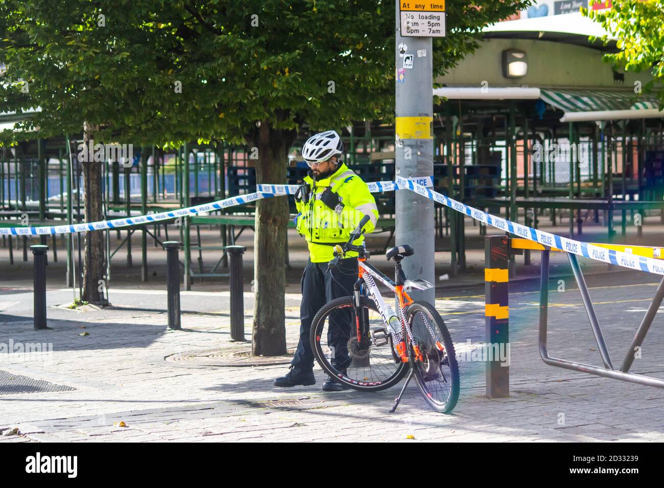 Ein männlicher Polizeibeamter der Gemeinde steht mit seinem Fahrrad, das eine Absperrung bewacht; West Midlands Police, Birmingham Stockfoto