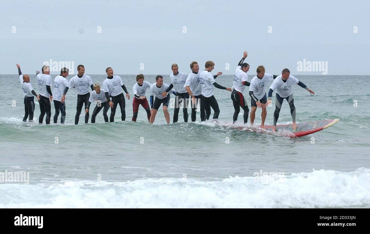 Mitglieder des 14-köpfigen Teams in St. Ives, Cornwall, während eines Versuchs auf den Weltrekord für die maximale Anzahl von Menschen, eine Welle auf einem riesigen Surfbrett zu reiten. Das Team aus 12 Männern und zwei Frauen war beim vierten Versuch erfolgreich. * mit einem massiven 37-Fuß-Board mit einem Gewicht von 400 Pfund. Stockfoto