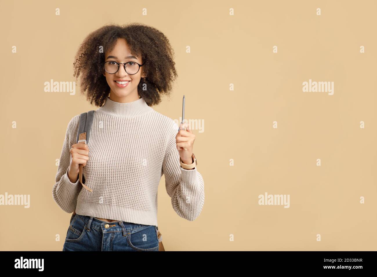Habe eine Idee, Wissen und Bildung Konzept. Nette afroamerikanische Frau Hipster mit Brille und Rucksack hebt Bleistift auf Stockfoto