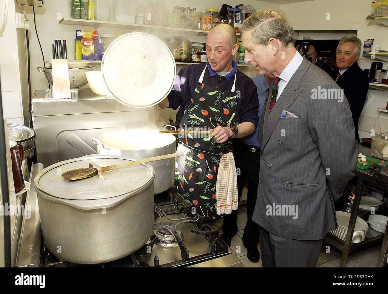 Der Prinz von Wales whatcht Hühnerkorma, das vom Old Crown Pub Chef Paul Johnson während eines Besuchs in Newmarket Village, Hesket, Cumbria zubereitet wird. Stockfoto