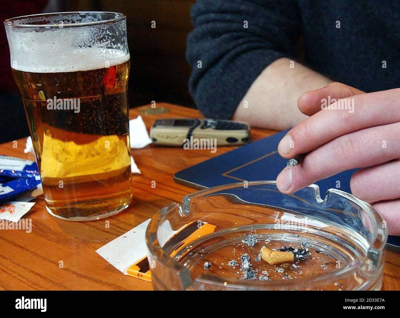 Ein Mitglied der Öffentlichkeit sitzt im ausgewiesenen Raucherbereich einer Bar im Zentrum von London. Aktivisten haben gesagt, dass durch das Rauchverbot an öffentlichen Orten mehr Menschenleben gerettet werden würden, als jedes Jahr bei Verkehrsunfällen verloren gehen. Anlässlich des No Smoking Day sagte der Direktor der Kampagne, Ben Youdan, dass das Verbot von Tabak in Pubs, Bars und allen Arbeitsplätzen 4,800 Menschenleben pro Jahr in England, Wales und Schottland retten würde. Stockfoto