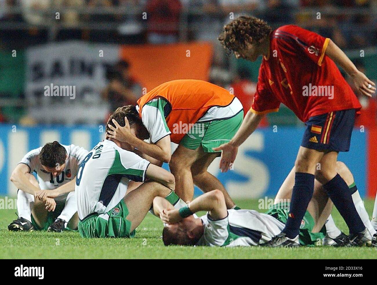 Irlands Robbie Keane (L) und Matt Holland (am Boden) werden von Teamkollege Jason McAteer (in orangefarbenem Lätzchen) getröstet, während Kevin Kilbane (2. Rechts) nach dem Elfmeterschießen nach dem Unentschieden von 1-1 während der WM von dem spanischen Spieler Puyol getröstet wird. *... zweites Rundenspiel zwischen Spanien und der Republik Irland in Suwon, Südkorea. Spanien gewann die Schießerei 3-2, um in das Viertelfinale zu kommen. Stockfoto