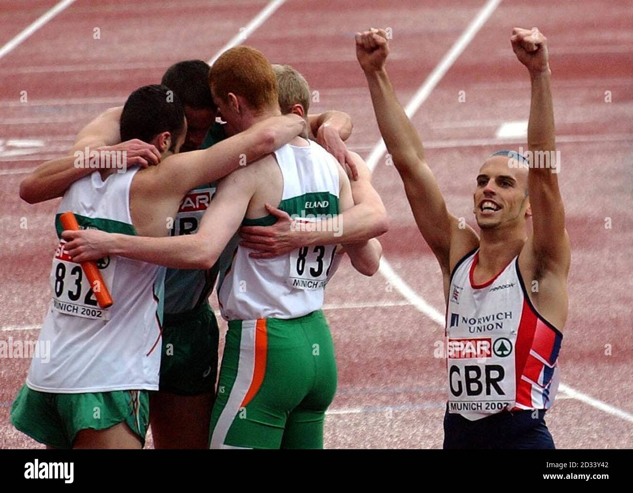 Der Engländer Matt Elias feiert, als das britische Team die 4x400-Staffel der Männer gewinnt, während sich der irische Kader nach dem sechsten Platz bei den Leichtathletik-Europameisterschaften in München gegenseitig tröstet. Stockfoto