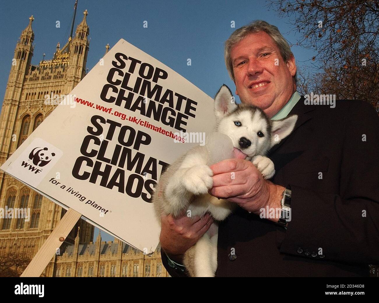 Ein Husky Welpe leckt Eis, gehalten von Minister Elliot Morley in Victoria Gardens vor dem House of Lords, London. Sie waren dort, um die verheerenden Auswirkungen des Klimawandels auf Menschen und Orte auf der ganzen Welt zu unterstreichen. Stockfoto