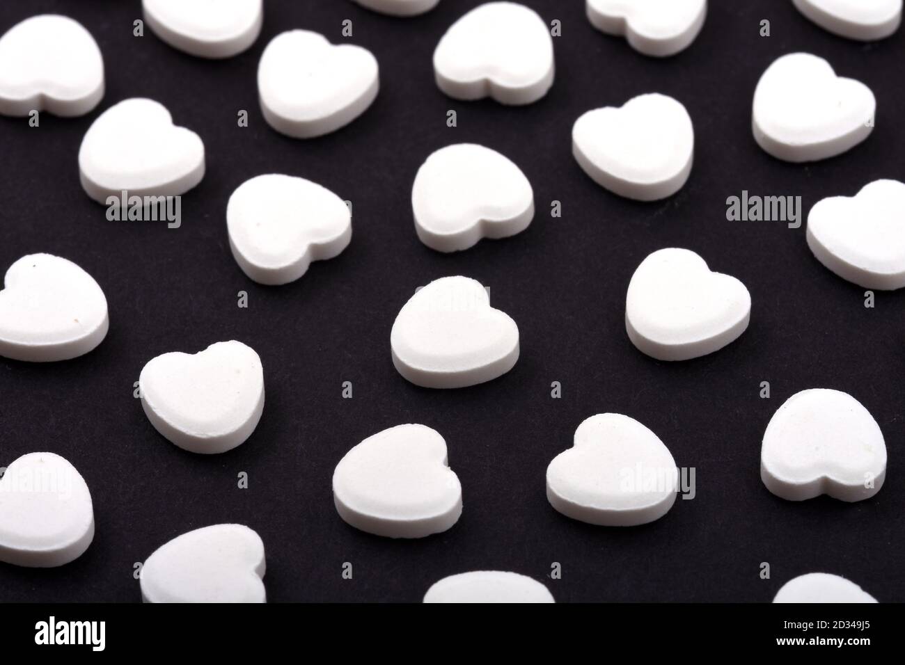 Herzförmige Pillen auf schwarzem Hintergrund. Medikamente, die Menschen helfen. Stockfoto