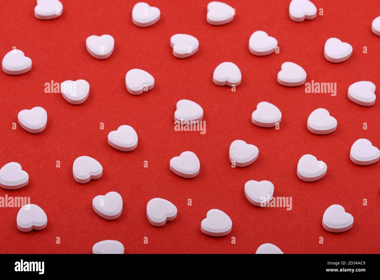 Herzförmige Pillen auf rotem Hintergrund. Medikamente, die Menschen helfen. Stockfoto