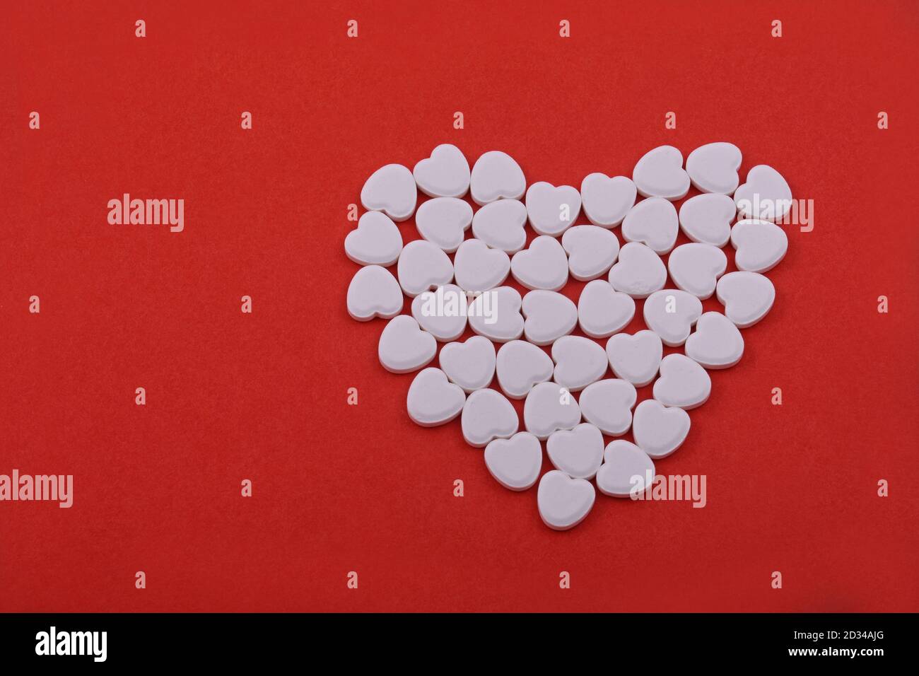 Herzform aus Herztabletten, herzförmige Pillen auf rotem Hintergrund. Medikamente, die Menschen helfen. Stockfoto