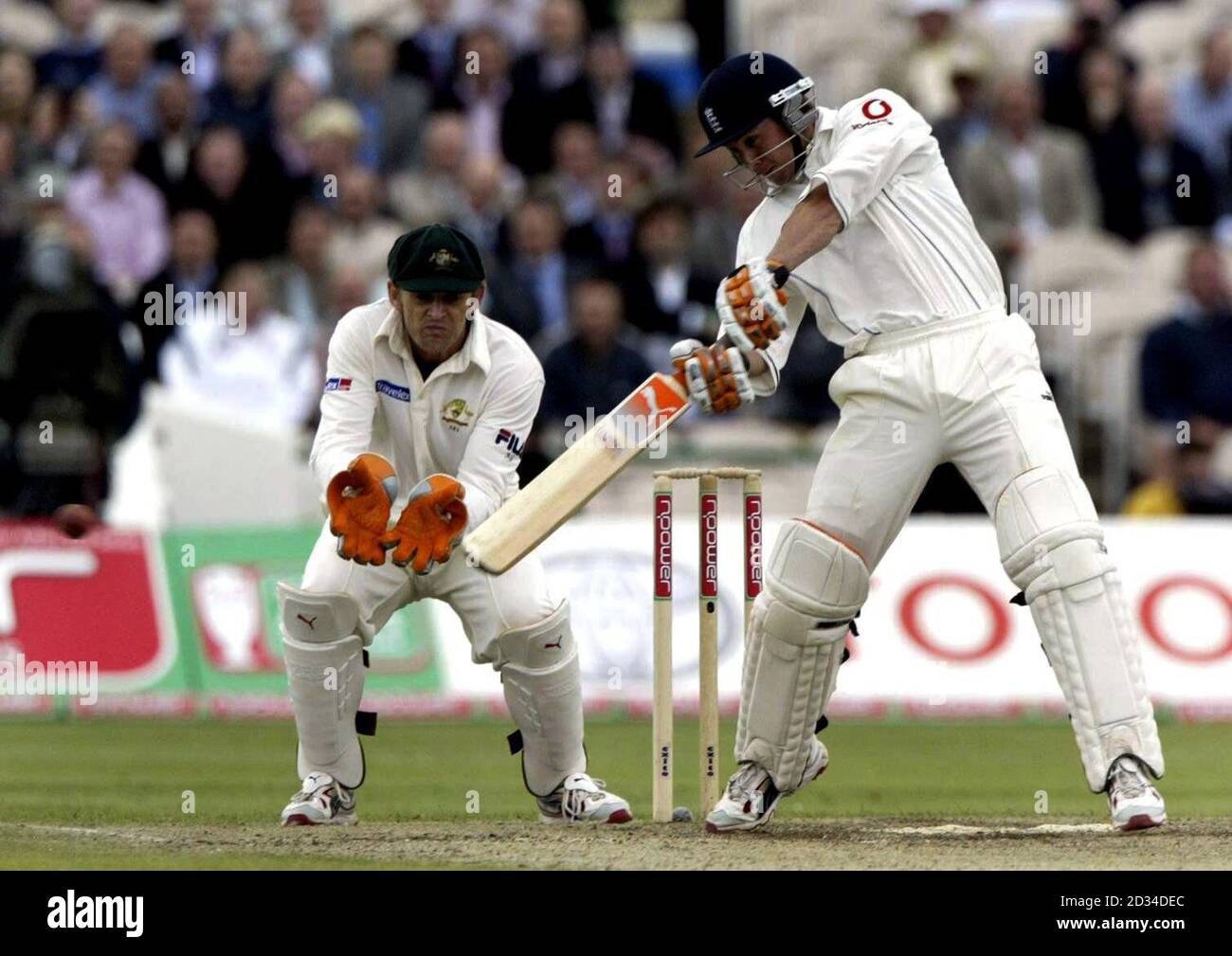 Der englische Batsman Geraint Jones spielt einen Cut-Shot vor Australiens Shane Warne, während der Wicketkeeper Adam Gilchrist (L) anschaut. Stockfoto