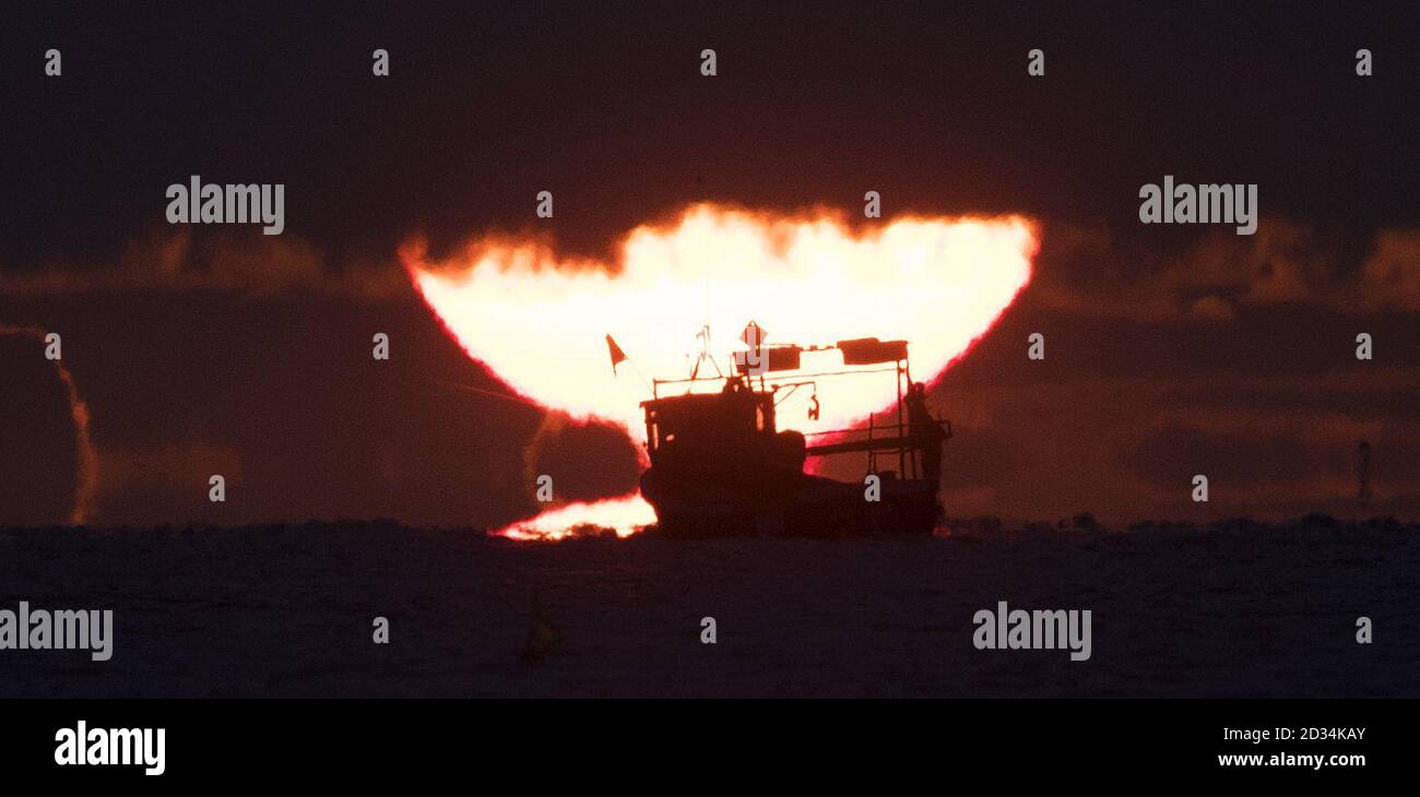 Die Sonne geht hinter einem Fischerboot von Blyth Pier in Northumberland, am letzten Tag des meteorologischen Sommers. Stockfoto