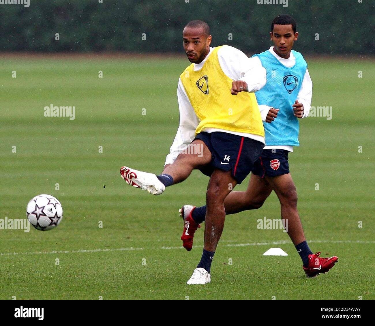 Thierry Henry von Arsenal passiert den Ball, während Theo Walcott (rechts) während einer Trainingseinheit in London Colney, Hertfordshire, schaut. Stockfoto