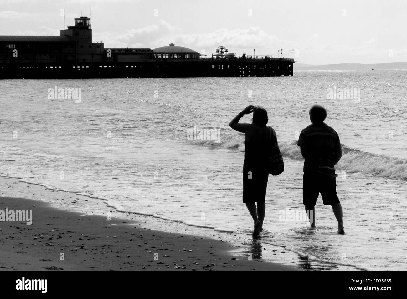 Ein paar Spaziergang paddeln im Meer, während sie in Richtung Westen zum Bournemouth Pier fahren. 15. Juli 2014. Foto: Neil Turner Stockfoto