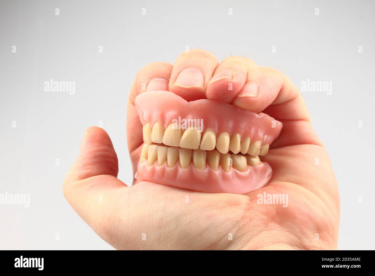 Zahnprothese in der menschlichen Hand isoliert auf der weißen Hintergrund Stockfoto