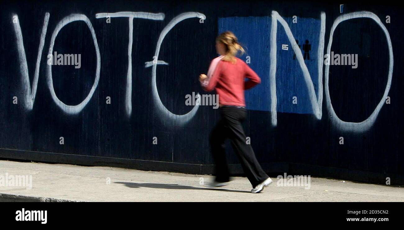 Eine Frau jagt an Graffiti vorbei, die beim bevorstehenden Referendum über den Vertrag von Lissabon im Stadtzentrum von Dublin ein Nein fordern. Stockfoto