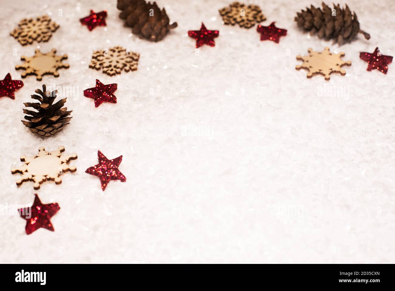 Weihnachtlicher Hintergrund, mit roten Glitzersternen, Holzschneepflakes, Kiefernzapfen und Schnee - anspruchsvoll, Luxus - Kopierraum Stockfoto