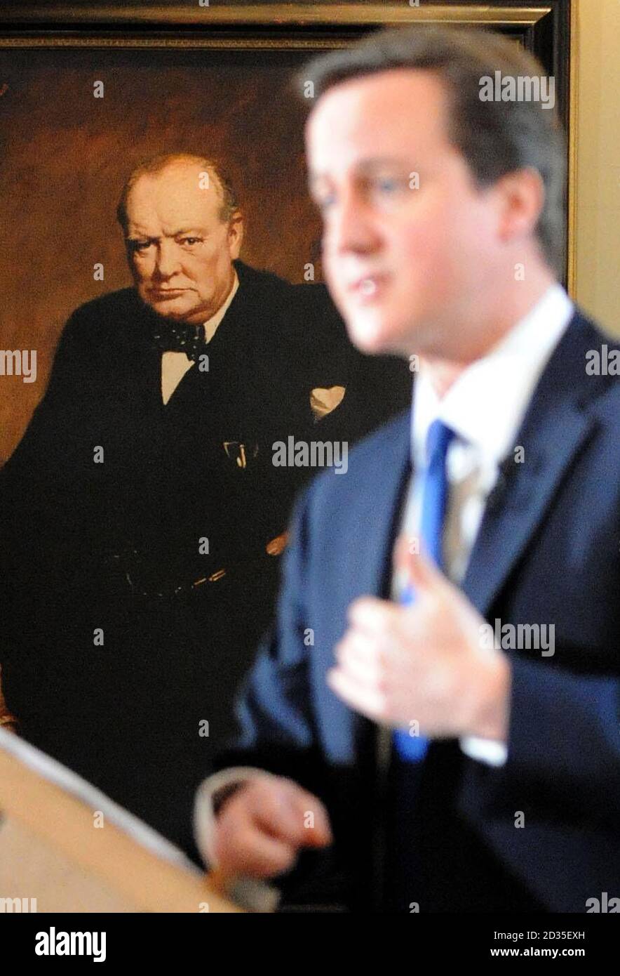 Der Vorsitzende der Konservativen Partei David Cameron wird von einem Porträt des Ministerpräsidenten Winston Churchill aus dem Krieg übersehen und spricht auf seiner regelmäßigen Pressekonferenz im St. Stephen's Club in Westminster. Stockfoto