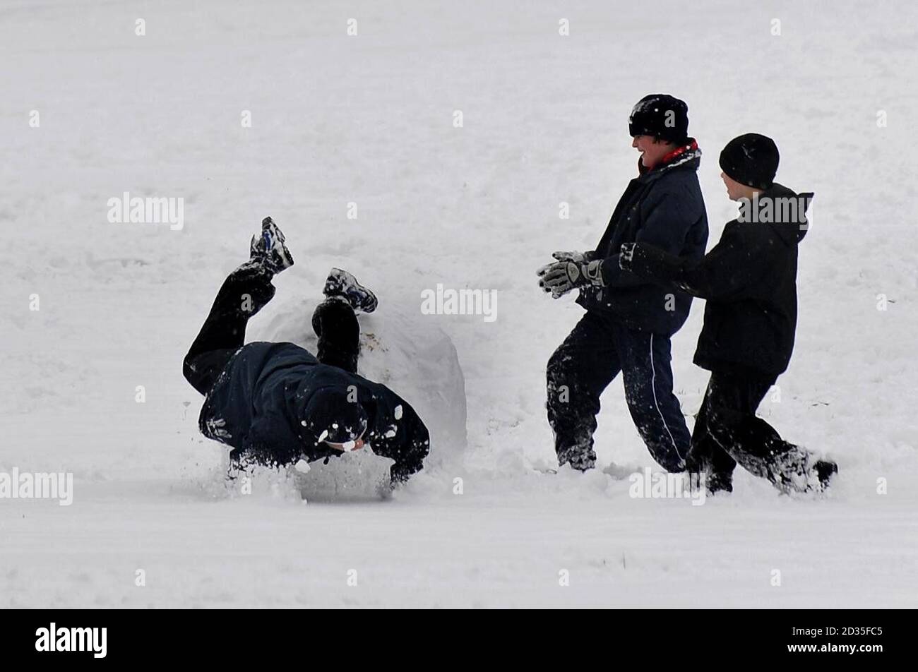 Ein Junge fällt in Harrow-on-the-Hill, Middlesex, nach starkem Schneefall in Großbritannien über einen großen Schneeball. Stockfoto