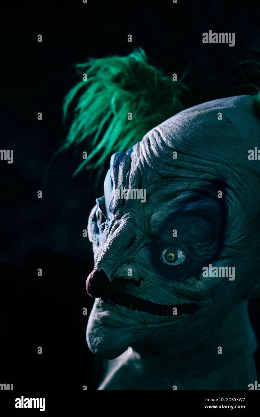 Nahaufnahme eines störenden bösen Clowns, mit grünen Haaren, vor schwarzem Hintergrund Stockfoto