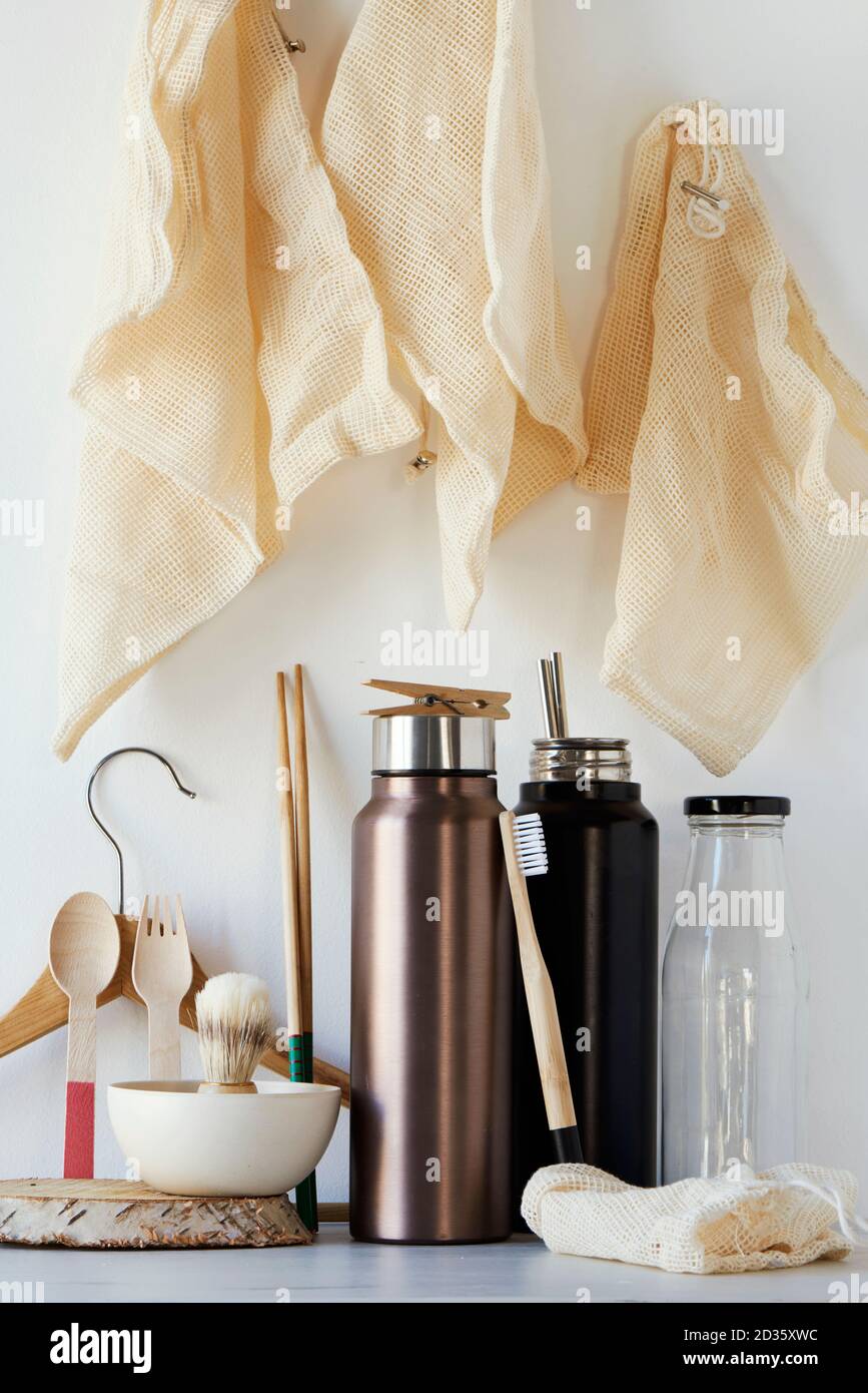 Ein Stapel von nachhaltigen Haushaltsgegenständen ohne Plastik, wie nachfüllbare Wasserflaschen, eine Glasflasche, Shopping-Mesh-Taschen, eine Rasierpinsel aus Holz und auch Stockfoto