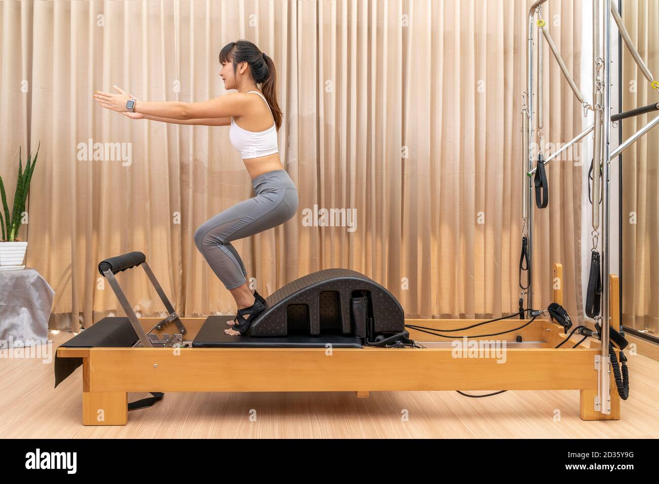 Junge asiatische Frau arbeiten auf Pilates Reformer Maschine während sie Training für Gesundheitsübungen Stockfoto