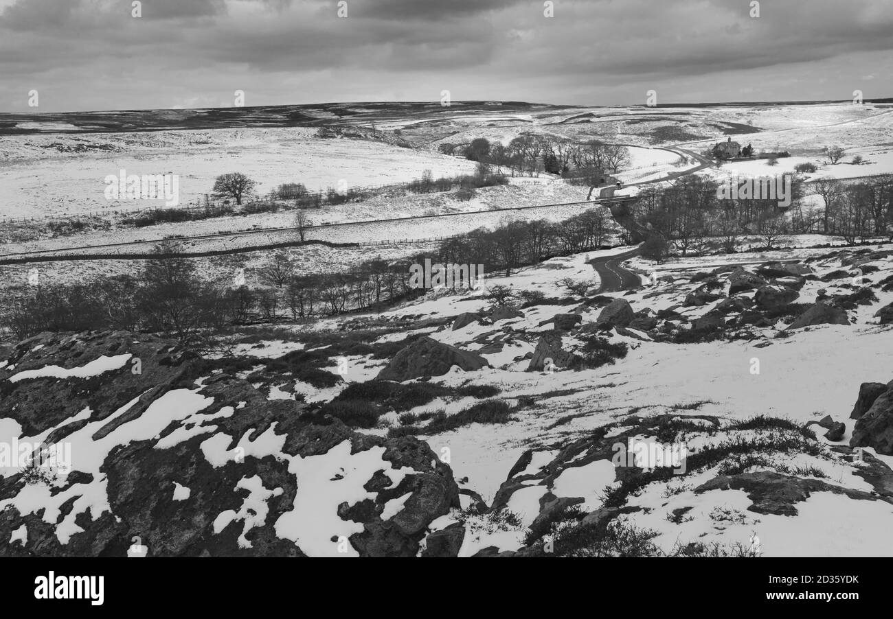 North York Moors nach Schneefall mit Felsen, Heide, Bäumen und Bauernhaus unter bewölkten Himmel im Winter in der Nähe von Goathland, Yorkshire, Großbritannien. Stockfoto