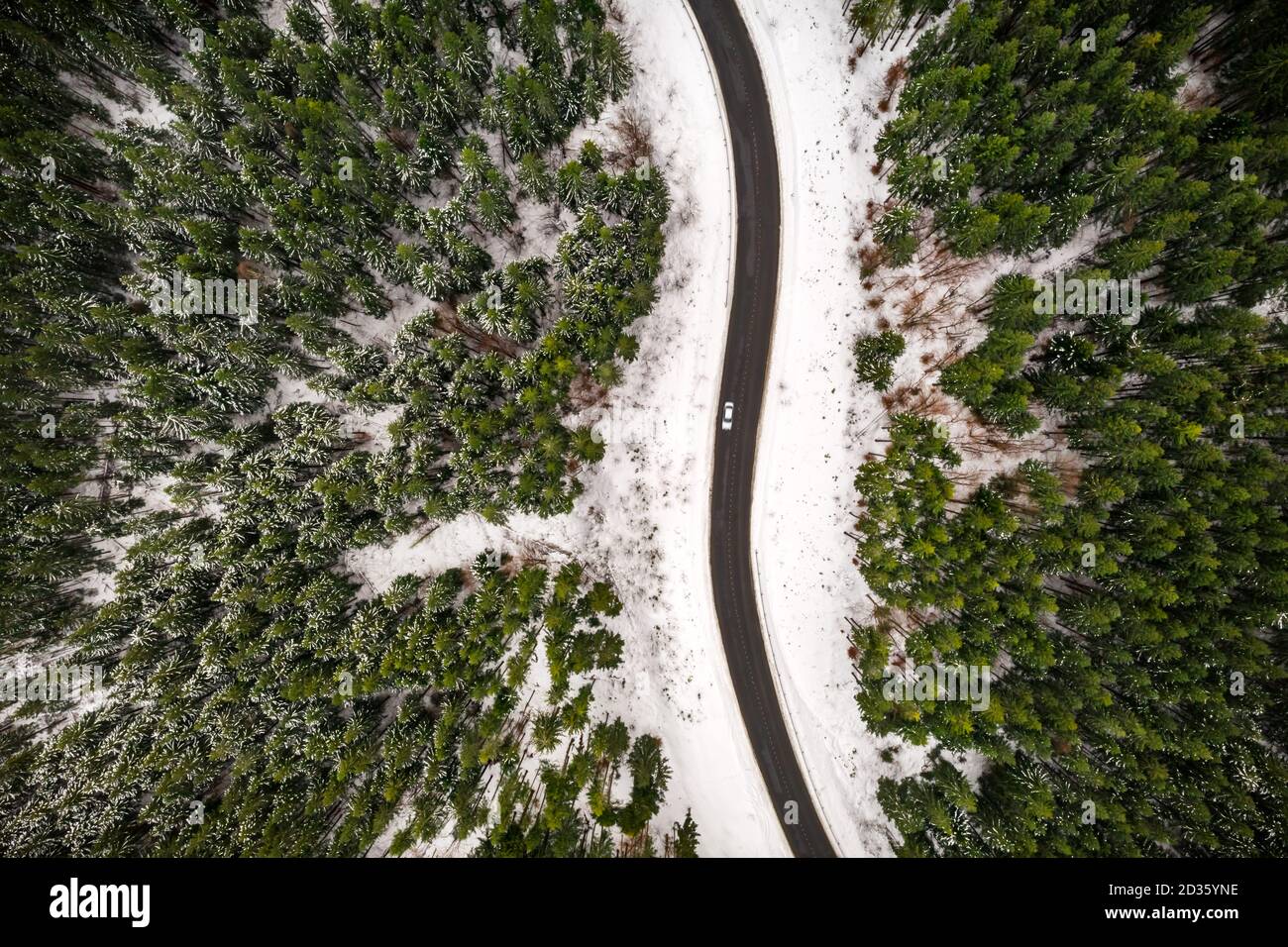 Flug über die Winterberge mit Straßenserpentin und verschneiten Wald. Draufsicht. Landschaftsfotografie Stockfoto