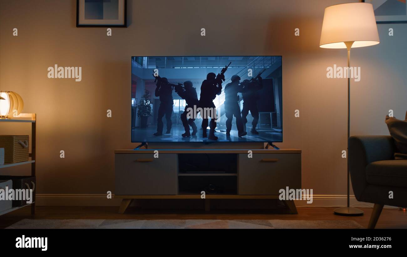 Aufnahme eines Fernsehens mit einem Action Movie mit Soldaten. Es ist Abend und Room at Home hat funktionierende Lampen. Stockfoto