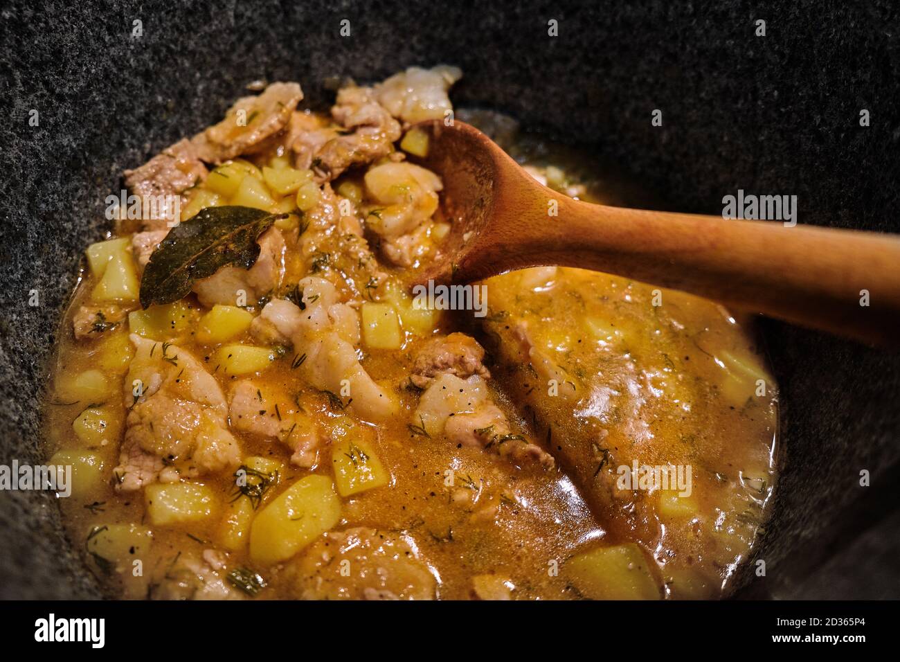 Kartoffeln und Fleisch in einem hohen Topf einkochen. Ein Holzlöffel mischt  das Ragout mit der Brühe. Lorbeerblatt in einem Eintopf von Kartoffeln und  Rindfleisch. Draufsicht auf coo Stockfotografie - Alamy
