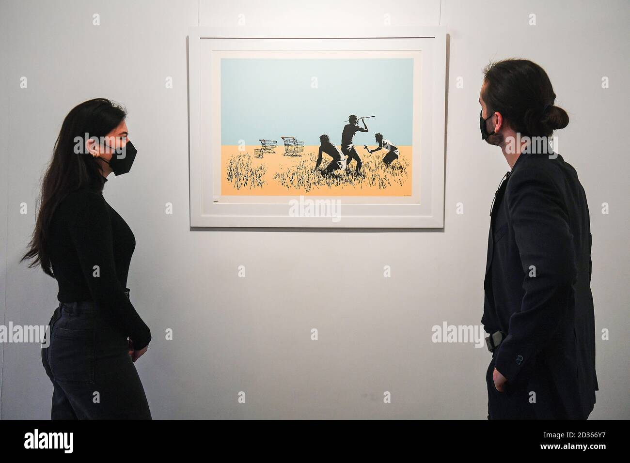 Galerieassistenten schauen sich einen limitierten Druck von Trolleys (Color) (2007) von Banksy an, einem Teil der Ausstellung "Catch Me If You Can" in der HOFA Gallery in Mayfair, London. Stockfoto