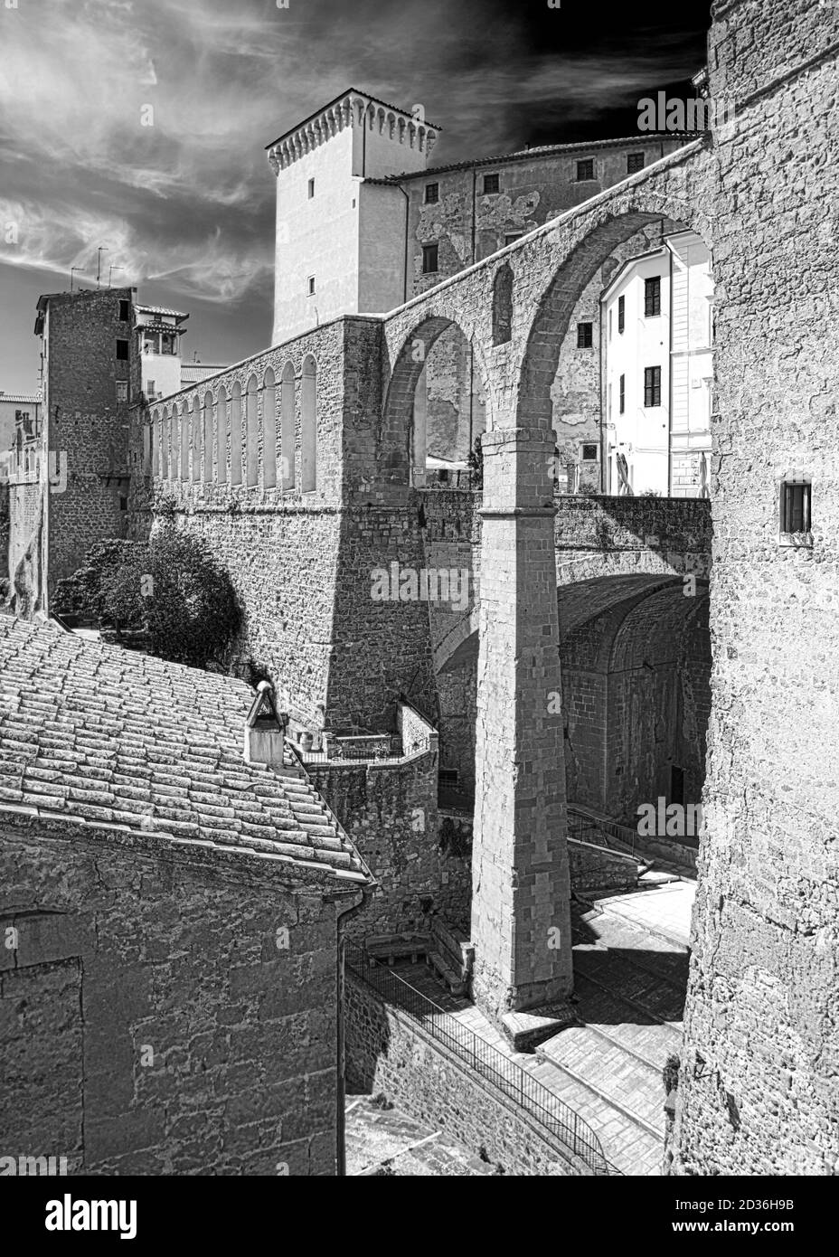 Das spektakuläre Medici Aquädukt von Pitigliano Stadt, mit Tufffelsen gebaut, und der Turm des Palazzo Orsini dahinter, die in den Himmel steigt. Stockfoto